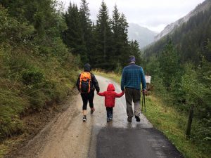 A family of three hiking outdoors with rain gear on